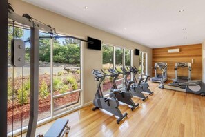 A gym with exercise equipment, large windows, and a wooden floor. - Phillip Island Resort Coastal Villa (Cowes)