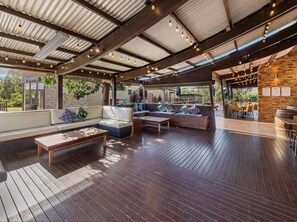 An outdoor patio area with wooden flooring, seating arrangements, and a bar area. - Phillip Island Resort Coastal Villa (Cowes)