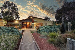A cafe & bar with a wooden deck leading to the entrance, surrounded by landscaped gardens. - Phillip Island Resort Coastal Villa (Cowes)