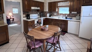 A kitchen with wooden cabinets, a stove, a sink, and a dining table with chairs.