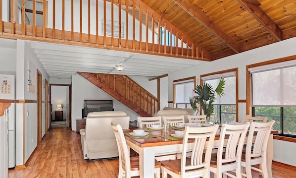 A spacious dining area with a wooden staircase, white walls, and large windows. - Seashell - Minutes walk to Beach. Phillip Island (Cape Woolamai)