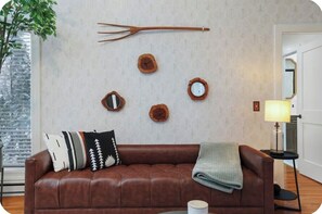 Ein braunes Ledersofa mit Decke, einer Pflanze und Wanduhren.