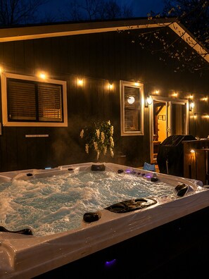 Un jacuzzi con pared exterior de madera, una ventana con persianas y una puerta que conduce a otra habitación.
