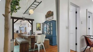 Ein Essbereich mit einem Holztisch, weißen Stühlen, einem blauen Schrank und einer Leiter.