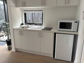 Een koffiezetapparaat/waterkoker, kookgerei, borden en bestek, eettafels