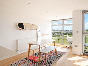 Une chambre moderne avec une table blanche, un tapis coloré et une grande fenêtre donnant sur la campagne.