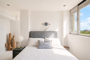 Une chambre à coucher avec un lit, une table de chevet, un attrape-rêves et une fenêtre donnant sur un beau paysage.