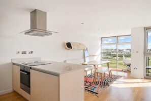 Cocina moderna con una isla grande, horno empotrado y vistas a un paisaje verde a través de amplios ventanales.