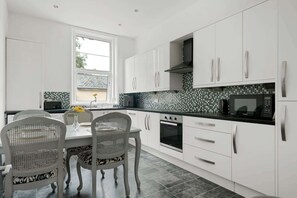 Une cuisine moderne avec des armoires blanches, un plan de travail noir et un pare-feu en carrelage.