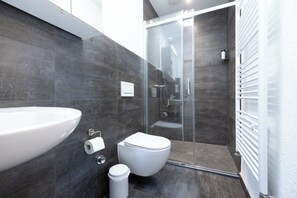 Un baño moderno con un lavamanos grande, inodoro y cabina de ducha de vidrio.