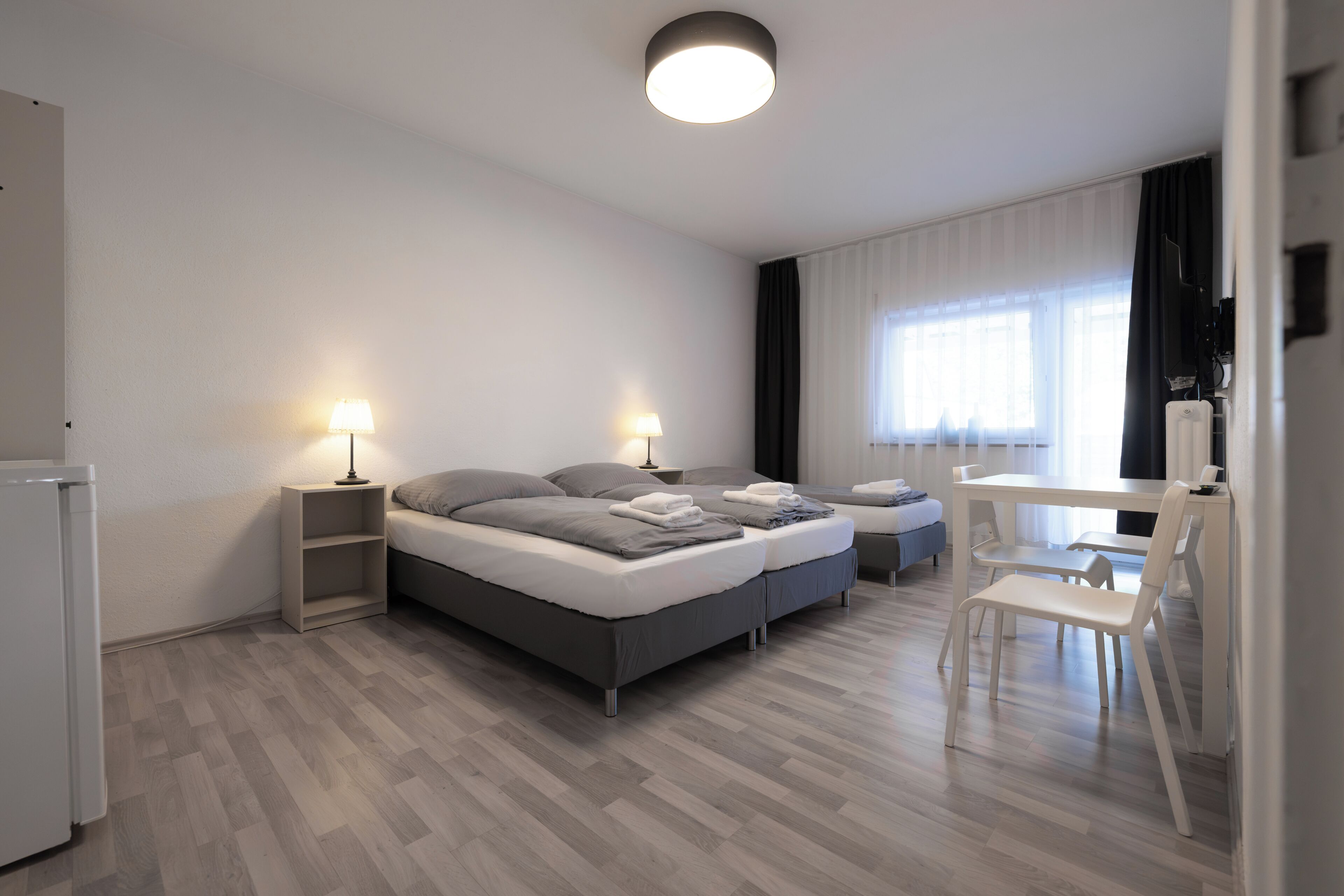 Un dormitorio moderno con cama, mesitas de noche, un escritorio y una silla.