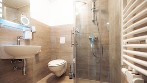 A modern bathroom with a glass shower enclosure, a white sink, and a toilet. - Hotel Three Corners (Grenzach-Wyhlen)
