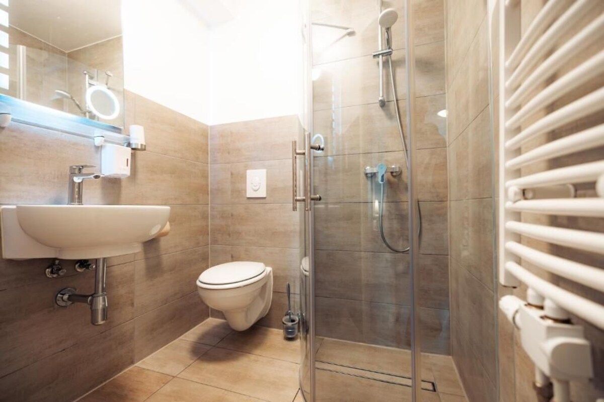 A modern bathroom with a glass shower enclosure, a white sink, and a toilet.