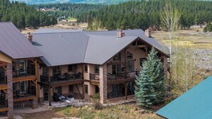 Un chalet à étages doté de balcons, d’une façade en pierre et offrant une vue sur une vallée boisée.
