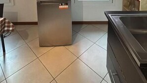 A kitchen with a stainless steel refrigerator, a sink, and a window with a view of a red building. - Rabi Rooms (Valbrenta)