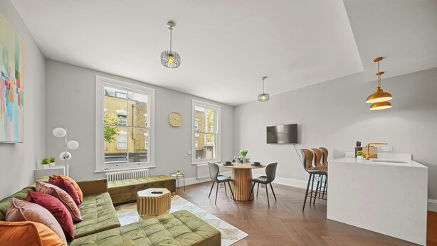 Ett modernt vardagsrum med en grön soffa, en matplats och en köksö.