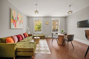 Ein modernes Wohnzimmer mit einem grünen Sofa, einem Essbereich und einem großen Fenster.