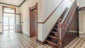 A hallway with a patterned floor, a wooden staircase, and a door leading to another room. - Large coastal home in the countryside of Amlwch - Pass the Keys (Amlwch)