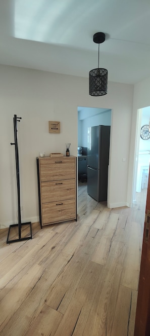 A modern kitchen with a refrigerator, wooden flooring, and a hanging light fixture. - Fully renovated 3-room apartment, quiet and close to downtown (Vence)