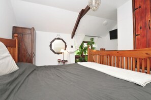 Ein Schlafzimmer mit einem hölzernen Bett, einem Nachttisch, einem Spiegel und einem Fenster mit Blick auf Grünflächen.