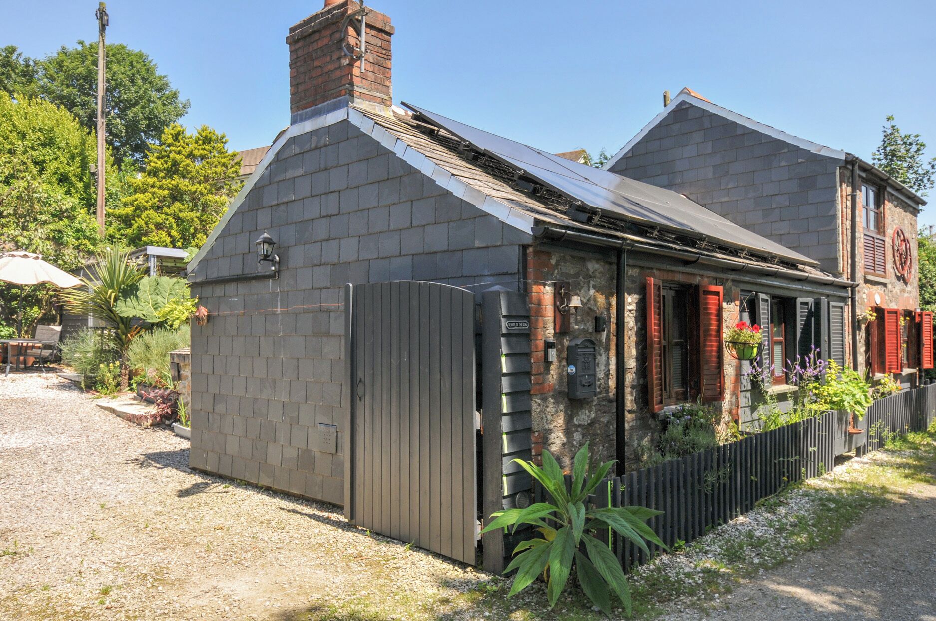 Une maison avec une façade en briques, un toit en métal et une clôture en bois.