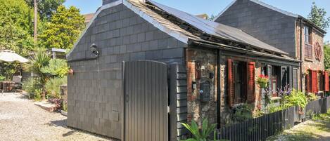 Une maison avec une façade en briques, un toit en métal et une clôture en bois.