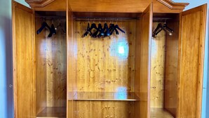 A wooden wardrobe with open doors, multiple shelves, and hanging space. - Biffi Rooms (Bassano del Grappa)