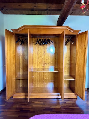 A wooden wardrobe with open doors, multiple shelves, and hanging space.