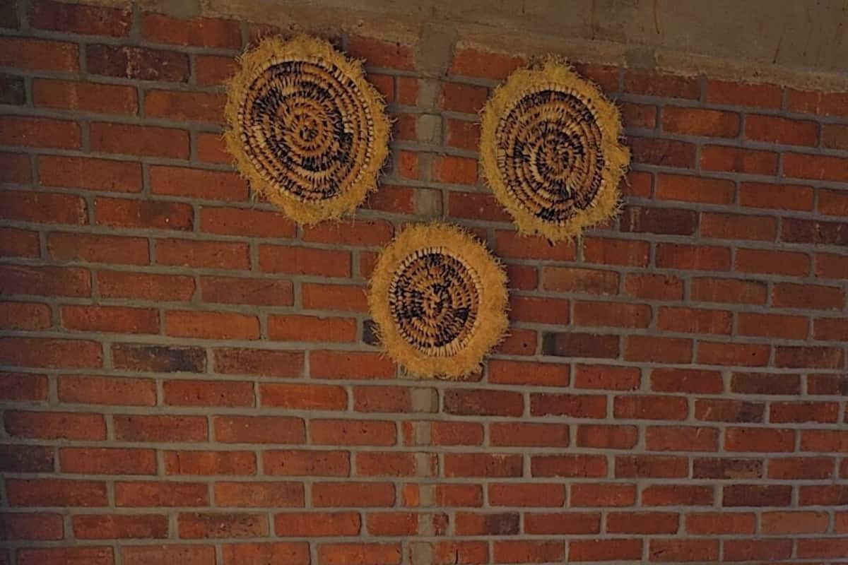 Een hotelkamer met een bakstenen muur, twee bedden, een houten hoofdeinde en een gestreepte deken.