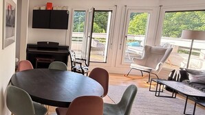 Ein modernes Wohnzimmer mit einem runden Tisch, mehreren Stühlen, einem Sofa, einem Couchtisch und einem Fernseher.