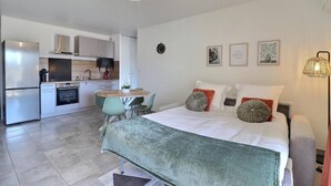Et moderne soveværelse med en stor seng, et spiseområde og et tekøkken.