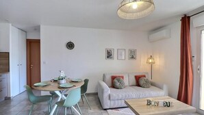 En moderne stue med sofa, sofabord, spiseplads med stole og en hængende lampe.