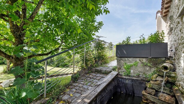Eine Steinbrücke über einen Kanal, eine Metalltreppe und ein Gebäude mit einer Steinmauer.
