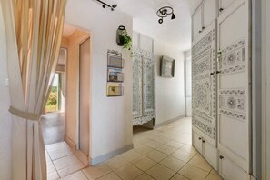 Un passadís amb portes amb disseny, una planta penjant i un llum fixat a la paret.