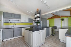 A modern kitchen with grey cabinets, a black countertop, and a central island.