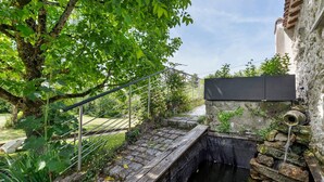 Een stenen brug over een waterkanaal, een metalen trap en een gebouw met een stenen muur.