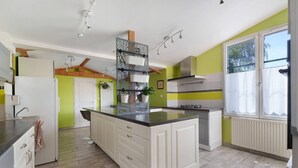 Een keuken met een centraal eiland, witte kasten, een ingebouwde oven en een raam met uitzicht.