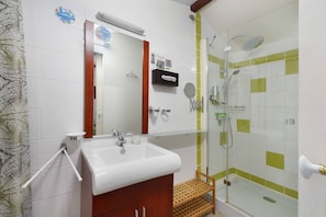 A bathroom with a sink, mirror, towel rack, shower, and glass-enclosed shower area.