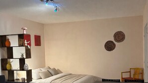Een slaapkamer met een bed, een bureau en een stoel. Er is een bank en een klein tafeltje met een lamp.