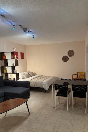 Ein Schlafzimmer mit Bett, Schreibtisch und Stuhl. Es gibt ein Sofa und einen kleinen Tisch mit einer Lampe.