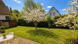Ein gepflegter Garten mit Rasen, einem Patio mit Gartenmöbeln und einem Haus im Hintergrund.