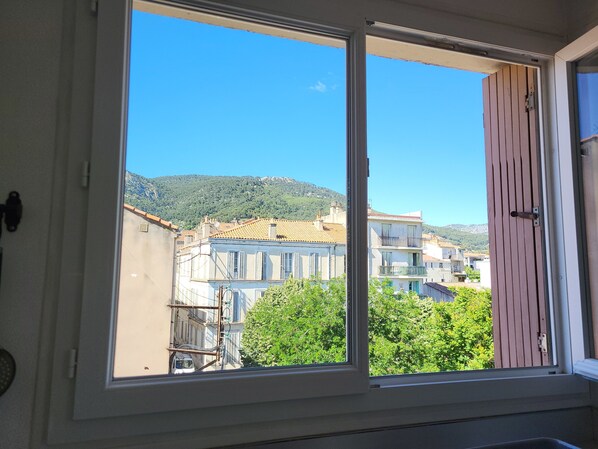 A window with a view of buildings and a mountain. - Bright apartment in Toulon (Toulon)