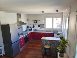 A kitchen with a refrigerator, stove, microwave, sink, and a small island with stools. - Bright apartment in Toulon (Toulon)