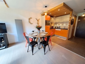 A modern dining area with a round table, chairs, and a television. - Bright apartment in the village center (Le Grand-Bornand)