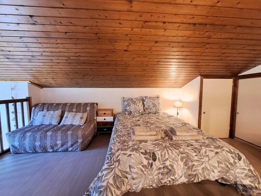 Ein Schlafzimmer mit Holzboden, einem Bett mit floralem Überwurf, einem Nachttisch und einem Beistelltisch.