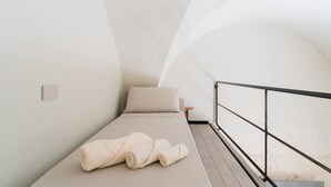 A small, single-bed room with a simple design, a mattress, pillows, a small bedside table, and a railing. - Suite 'Luxury Rooms - Erika' with Wi-Fi and Air Conditioning (Alezio)