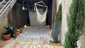 En terrasse med hængekøje, krukker med planter og en trappe.
