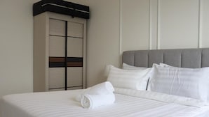 Une chambre d’hôtel comprenant un lit, des oreillers, une tête de lit et une armoire.