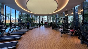 Une salle de sport équipée de tapis de course, d’appareils de musculation et dotée d’une grande verrière circulaire.