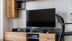 Ein modernes Wohnzimmer mit Flachbildfernseher, einer Holz-Unterhaltungseinheit und einem schwarzen Sessel.